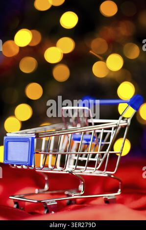 Svuotare il carrello della spesa contro le luci sfocate sull'albero di natale Foto Stock