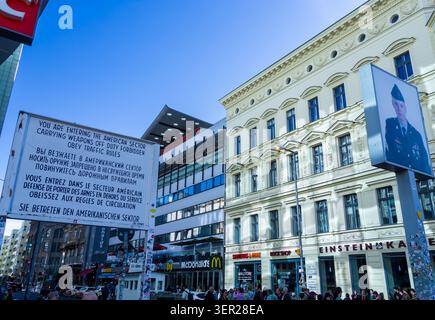 Storico cartello del settore americano al Checkpoint Charlie di Berlino, Germania, con la vita moderna della città, visitatori internazionali ed edifici commerciali. Foto Stock