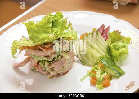 Insalata di diversi tipi di salsicce, cetrioli, peperoni, lattuga con panna acida salsa Foto Stock