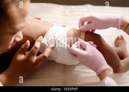 Black Mother Holding Baby durante la visita pediatrica Foto Stock