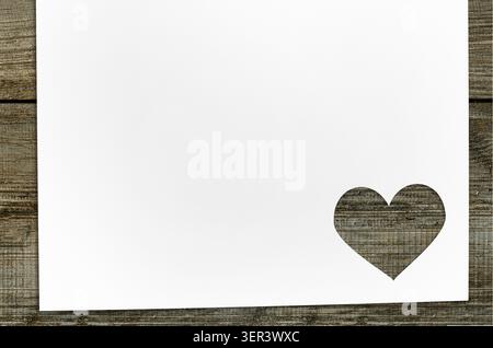 Carta tagliata a forma di cuore per il biglietto d'auguri del giorno di Valenine su un tavolo di legno Foto Stock