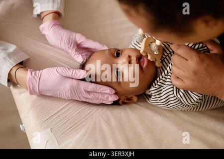 Ritratto del bambino nero che riceve un assegno pediatrico con la madre Foto Stock