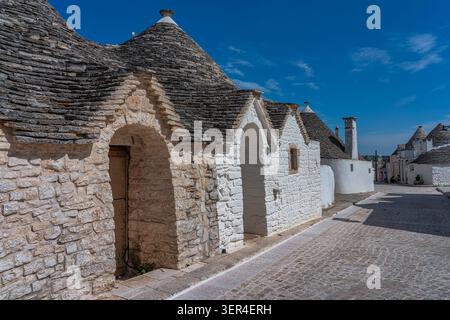 Uno scorcio dei tradizionali trulli nel quartiere di Aia piccola, con i loro caratteristici tetti conici in pietra e le pareti dipinte di bianco. Alberobello Foto Stock