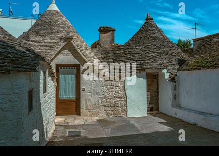 Uno scorcio dei tradizionali trulli nel quartiere di Aia piccola, con i loro caratteristici tetti conici in pietra e le pareti dipinte di bianco. Alberobello Foto Stock