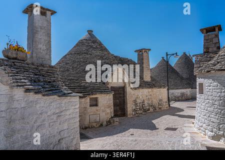 Uno scorcio dei tradizionali trulli nel quartiere di Aia piccola, con i loro caratteristici tetti conici in pietra e le pareti dipinte di bianco. Alberobello Foto Stock