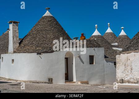 Uno scorcio dei tradizionali trulli nel quartiere di Aia piccola, con i loro caratteristici tetti conici in pietra e le pareti dipinte di bianco. Alberobello Foto Stock