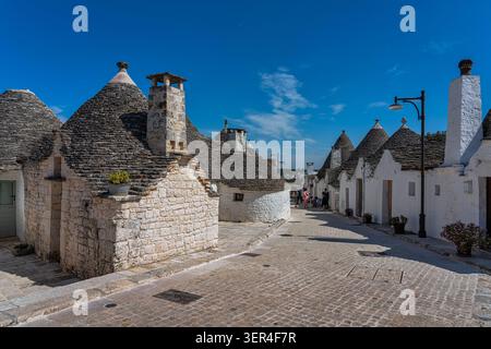 Uno scorcio dei tradizionali trulli nel quartiere di Aia piccola, con i loro caratteristici tetti conici in pietra e le pareti dipinte di bianco. Alberobello Foto Stock