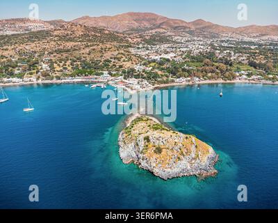 Vista aerea che mostra l'Isola dei conigli e l'affascinante villaggio di Gumusluk, Bodrum con barche nelle acque blu del Mar Egeo a Turkiye Foto Stock