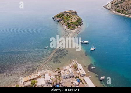 Vista aerea della baia di Gumusluk che mostra le barche nel mare turchese dell'Egeo con il piccolo villaggio di pescatori e le isole circostanti a Turkiye Foto Stock