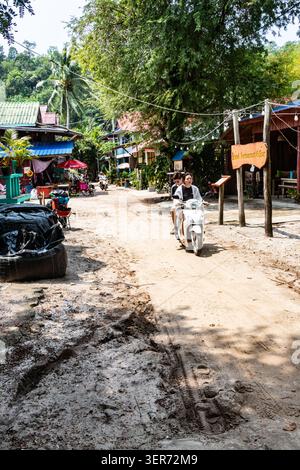 Scooter su piccola strada sterrata a Sok San, un piccolo villaggio di pescatori ai margini di Long Beach, a Koh Rong, Cambogia. Foto Stock