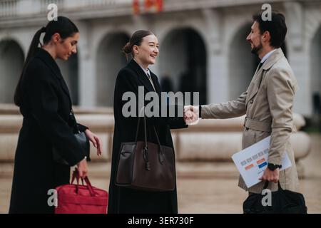 I professionisti d'affari salutano e stringono la mano all'aperto durante una riunione formale in città Foto Stock