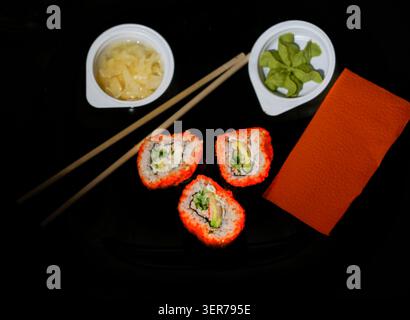 Rotoli di sushi con wasabi e zenzero su sfondo nero Foto Stock