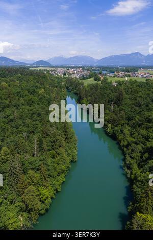Un fiume scorre attraverso una foresta verde con alberi su entrambi i lati. L'area mostra un paesaggio naturale con acque cristalline e montagne lontane. Foto Stock