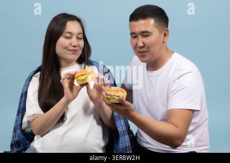 Giovane e bella donna in piedi e mangiano gustosi hamburger insieme Foto Stock