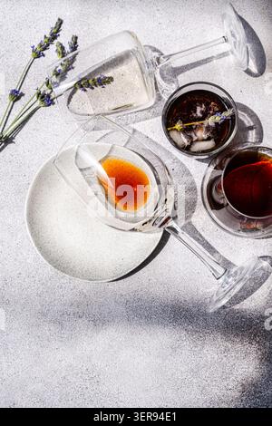 Una sofisticata disposizione di caffè ghiacciato e bicchieri da vino in una giornata di sole, impreziosita da delicata lavanda, cattura l'essenza della rigenerante summe Foto Stock