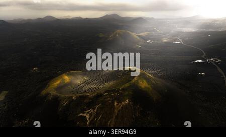 Vista aerea del paesaggio vulcanico dei vigneti di Lanzarote all'alba, dove la luce magica pascolava campi di lava scura, coni e pozzi d'uva a la Geria, CAN Foto Stock