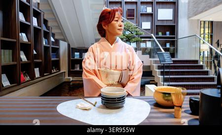 Tradizionale cerimonia giapponese del tè matcha con una donna che indossa un kimono a Tokyo, preparando tè verde in polvere con chasen e ciotola da tè in un ambiente tranquillo e moderno Foto Stock