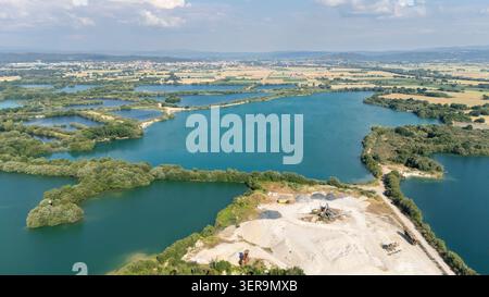 Vista aerea che mostra il sito minerario aggregato con attrezzature di lavorazione, vasti pali di sabbia e numerosi laghi artificiali turchesi Foto Stock