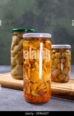 Vari funghi commestibili conservati in vasetti di vetro sigillati, con agarica e bottoni al miele dorato, che offrono un metodo tradizionale di conservazione degli alimenti Foto Stock