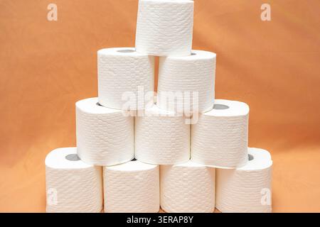 Pila di rotoli di carta igienica bianca disposti a piramide su sfondo semplice. Diversi rotoli di carta igienica impilati a piramide su una superficie piana. com Foto Stock