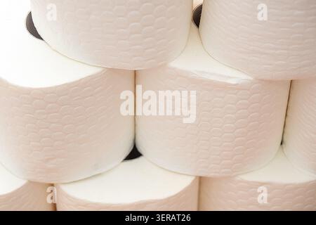 Rotoli di asciugamani di carta bianca impilati in una dispensa della cucina con un ripiano in legno e illuminazione calda durante il giorno. dispensa da cucina, diversi rotoli di asciugamani di carta bianca sono impilati ordinatamente su un ripiano di legno. Foto Stock