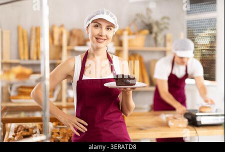 Giovane venditore che tiene un pezzo di pasta in un piatto di carta Foto Stock