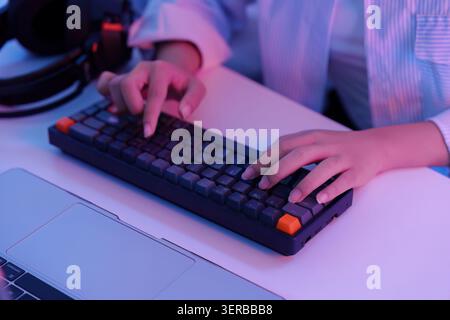 Digitazione a mani tagliate sulla tastiera meccanica per videogame per la tecnologia digitale e l'intrattenimento al computer Foto Stock