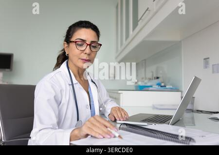 Grave anziano medico professionista che esamina le cartelle cliniche Foto Stock