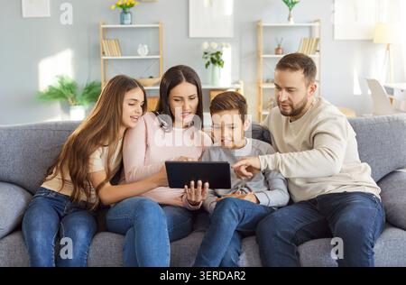 Giocosa divertente famiglia a casa tablet guardare online, genitori e bambini adulti felici eccitati di gioia Foto Stock