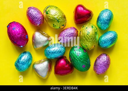 Caramelle al cioccolato in lamina multicolore su sfondo giallo. Vari prodotti dolciari. Foto Stock