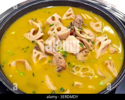 La zuppa cinese presenta spesse fette di tenera radice di loto e saporite ossa di maiale sospese in un ricco brodo dorato Foto Stock