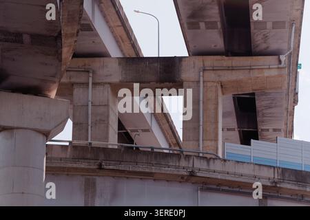 Vista verso l'alto dei cavalcavia multilivello in cemento a Taipei che mostra tubi, pilastri e ponti stradali stratificati contro un cielo pallido coperto. Foto Stock