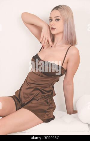 Giovane donna seduta sul pavimento che posa su sfondo blu Foto Stock