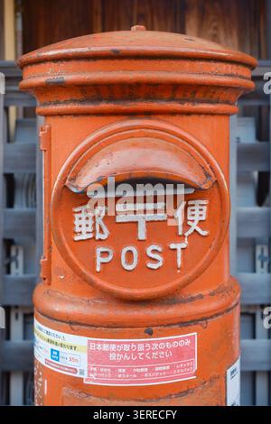 Classico box da posta a colonna in ghisa rossa con scritta kanji giapponese e testo inglese all'aperto, Kyoto, Giappone Foto Stock