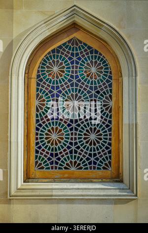 Questa vista ravvicinata cattura una finestra Shebeke decorata, caratterizzata da intricati motivi geometrici di vetrate colorate in vari colori, ambientate in un arco classico Foto Stock