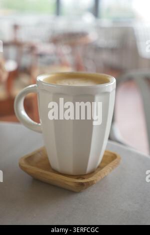 Una tazza di caffè si siede su un vassoio di legno in un caffè Foto Stock