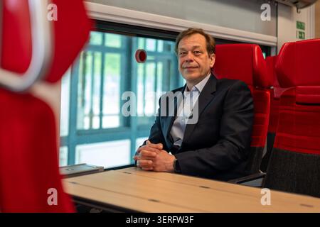 Un uomo di mezza età siede a un tavolo all'interno di una moderna carrozza ferroviaria Foto Stock