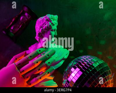 Antica scultura in marmo con mano robotica che si avvicina alla sfera da discoteca illuminata da luci al neon Foto Stock