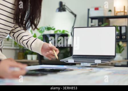 Modello di notebook con schermo bianco vuoto sulla scrivania in un moderno ufficio domestico Foto Stock