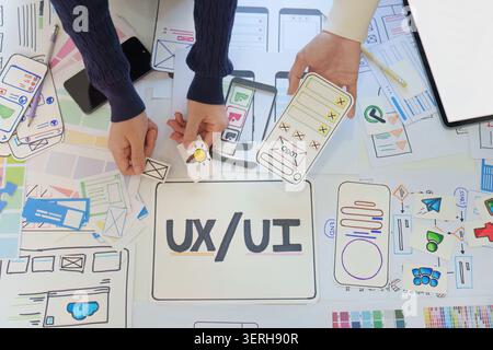 Vista dall'alto dei progettisti che eseguono brainstorming sull'interfaccia delle app mobili con prototipi di carta Foto Stock