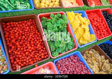Colorati frutti secchi e canditi, tra cui kiwi, mango, ciliegie e spuntini di frutta assortiti esposti in vassoi presso un mercato locale nel Kashmir. Foto Stock