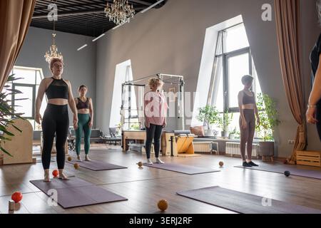 Un gruppo di donne mature che praticano pilates o yoga su tappetini con palle da allenatore negli interni moderni dello studio pilates. Longevità, articolazioni mobili sane e colonna vertebrale Foto Stock