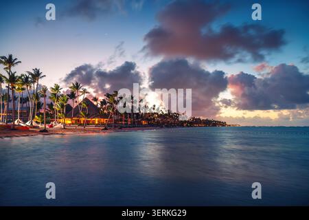 Lussuosa spiaggia tropicale con palme e bungalow al tramonto a Punta Cana, Repubblica Dominicana Foto Stock