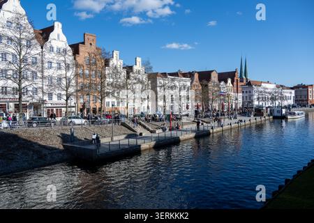 Vista panoramica sul lungomare di Lübeck con edifici storici, caffetterie e guglie lungo il fiume trave nello Schleswig-Holstein, Germania. Foto Stock