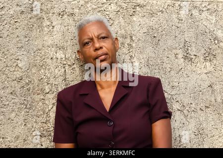 Inquadratura a spalla di una donna contro un muro ruvido Foto Stock