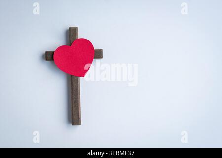 Cuore di carta rossa sulla cima del crocifisso a croce di legno. Isolato su sfondo bianco. Foto Stock