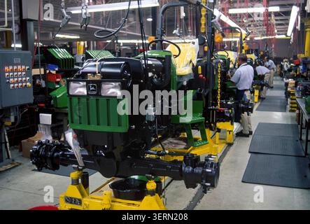 I trattori John Deere si spostano lungo un'affollata linea di assemblaggio di una fabbrica, dove i lavoratori costruiscono macchinari agricoli ecologici in un moderno stabilimento di produzione. Foto Stock