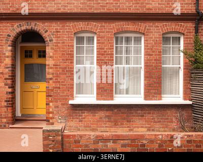 LONDRA - casa in mattoni rossi con porta d'ingresso gialla e finestre bianche Foto Stock
