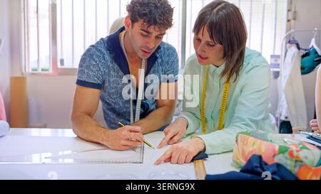 Stilisti di moda che collaborano a un nuovo modello di abbigliamento in officina Foto Stock