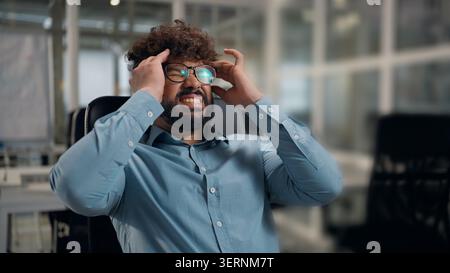 Indù infelice uomo d'affari arabo che si sente male tenendo la testa difficile pensare sentire mal di testa pressione alta uomo d'affari etnico che soffre di lavorare Foto Stock